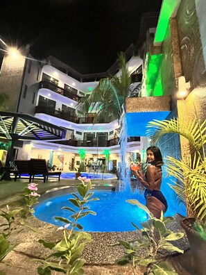 A multi-level hotel with a central courtyard featuring a water fountain, benches, and potted plants. - Hotel Aryia (Máncora)