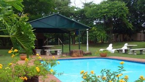 A swimming pool with a covered seating area and outdoor furniture. - Ascot Inn (Pietermaritzburg)
