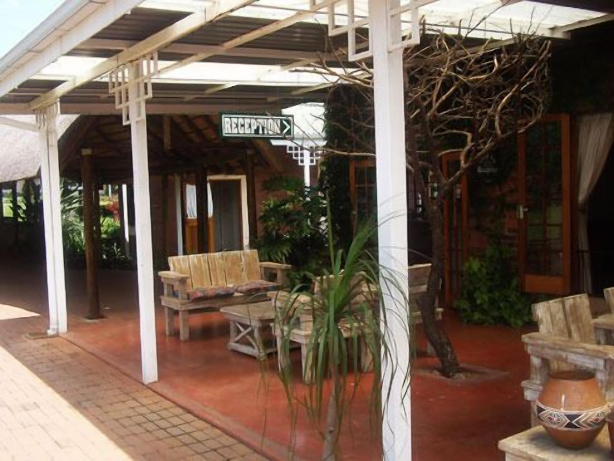 Zona de recepción con un banco de madera, una planta en maceta y un cartel que indica la recepción.