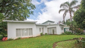 Una casa blanca de dos pisos con un pequeño jardín delantero y una palmera.
