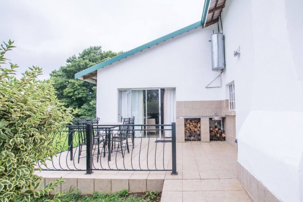 A modern house with a patio, a metal fence, and a stack of firewood.