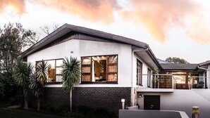 A modern two-story house with a balcony, large windows, and a garage. - Four Palms Accommodation (Cape Town)