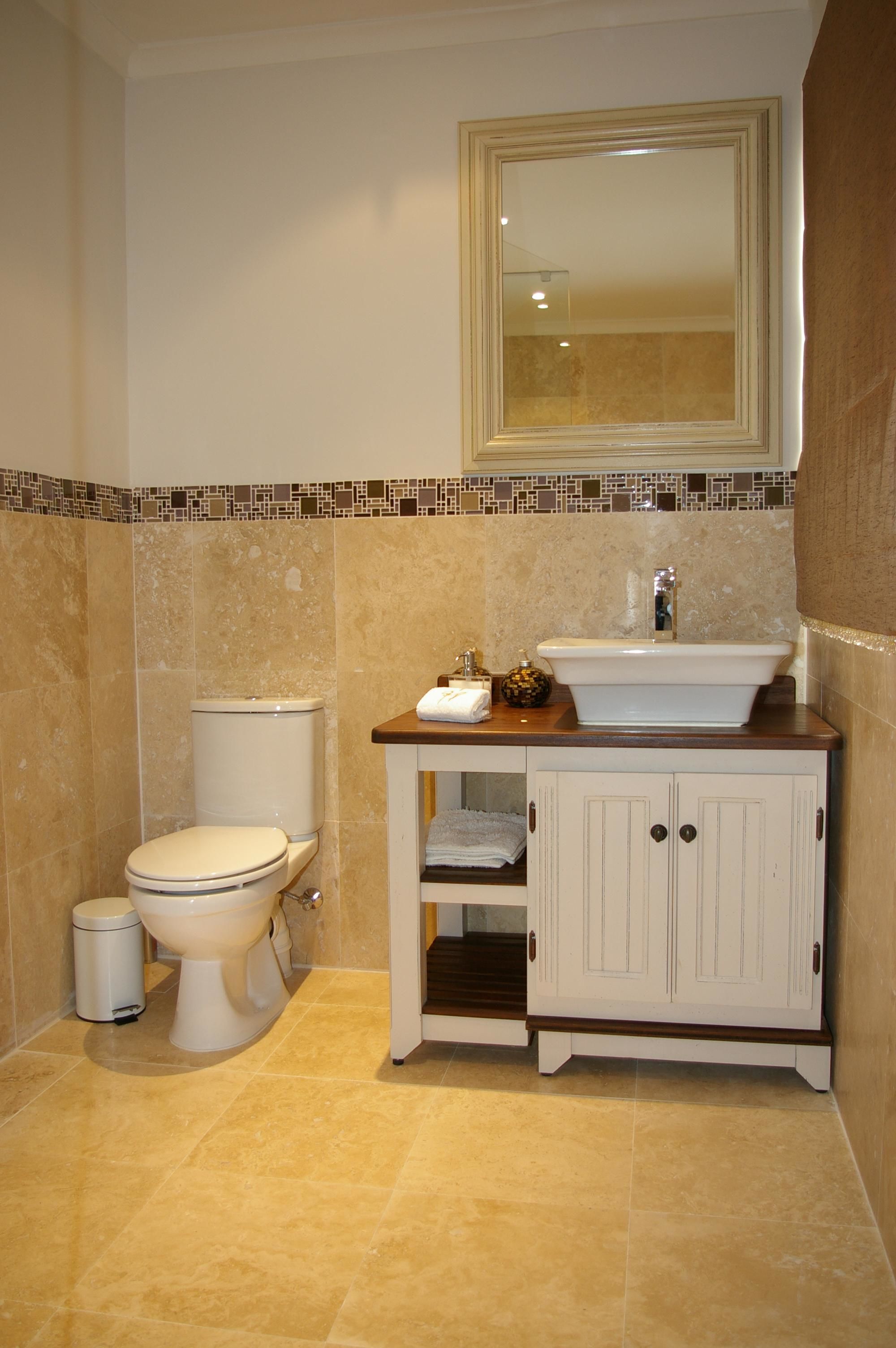 Une salle de bain équipée de toilettes, d’un lavabo, d’un meuble et d’un miroir.