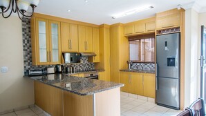 Een moderne keuken met houten kastjes, granieten werkbladen, een roestvrijstalen koelkast en een ingebouwde oven.
