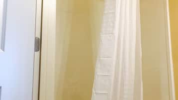 Un box de ducha con puerta de cristal, una cortina de ducha blanca y una bañera.