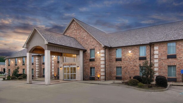 A brick building with a covered entrance and multiple windows. - Days Inn & Suites by Wyndham Florence/Jackson Area (Florence)