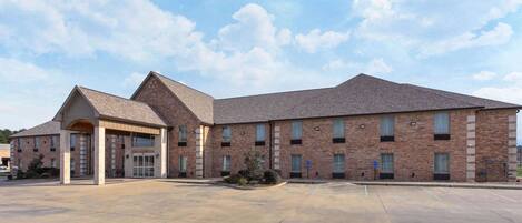 A large brick building with a covered entrance and a spacious parking lot.