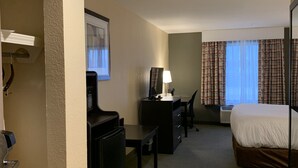 A hotel room with a bed, desk, chair, and a small kitchenette area. - Days Inn & Suites by Wyndham Florence/Jackson Area (Florence)