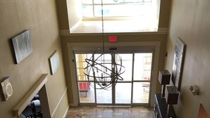 A lobby with a stone floor, a chandelier, a reception desk, and a view of the outside through large windows. - Days Inn & Suites by Wyndham Florence/Jackson Area (Florence)
