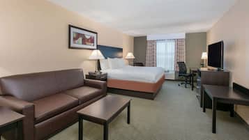 Une chambre d’hôtel équipée d’un lit, d’un canapé, d’un bureau, d’une chaise, d’une télévision et d’une fenêtre avec des rideaux.
