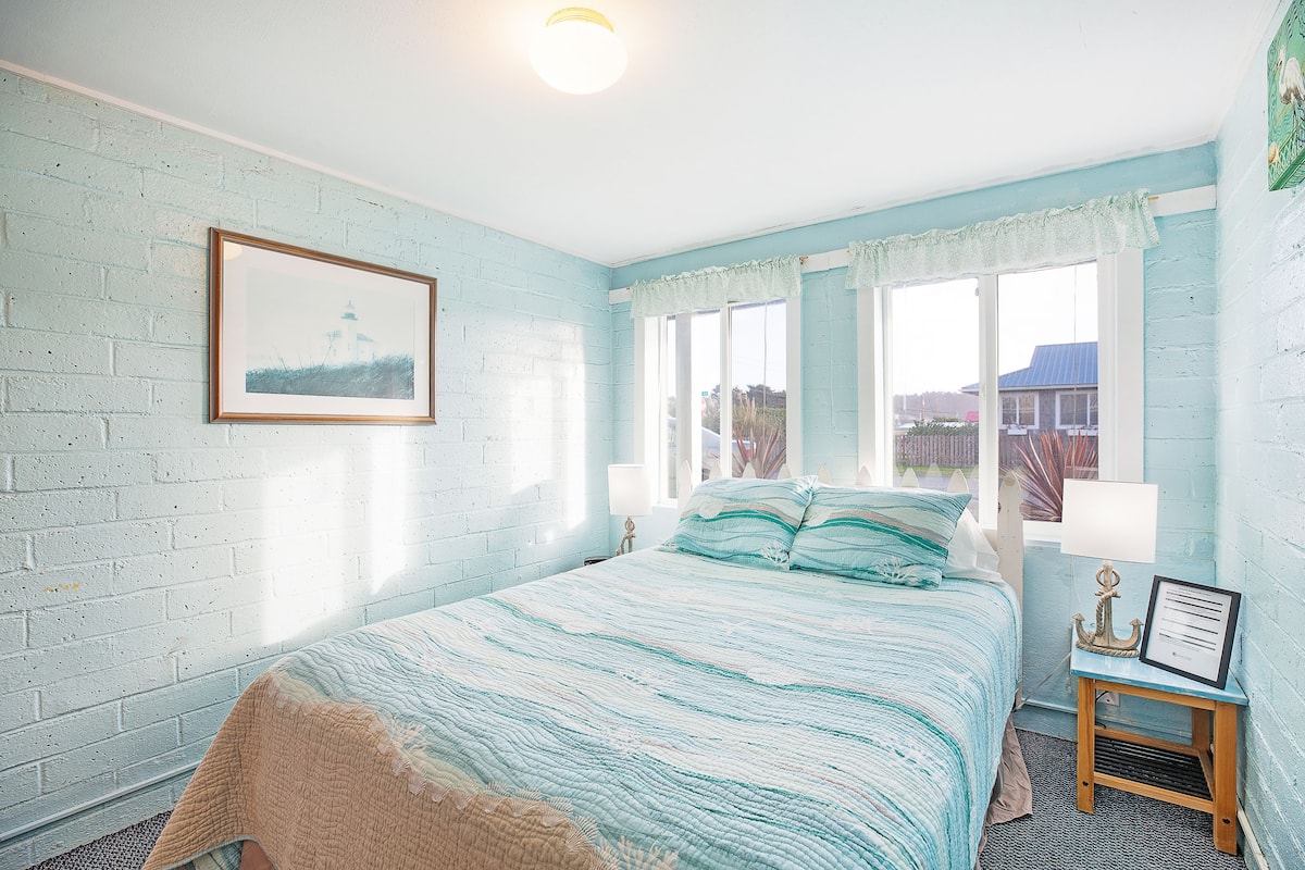 A bedroom with a bed, a nightstand, a lamp, and a framed picture on the wall.