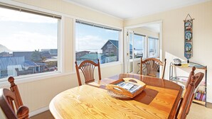A dining area with a wooden table, four chairs, and a view of buildings through large windows. - Sand Dollar Condos (Pacific Beach)