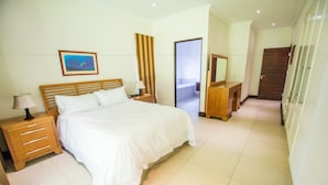 A bedroom with a large bed, wooden nightstands, a dresser, and a mirror.