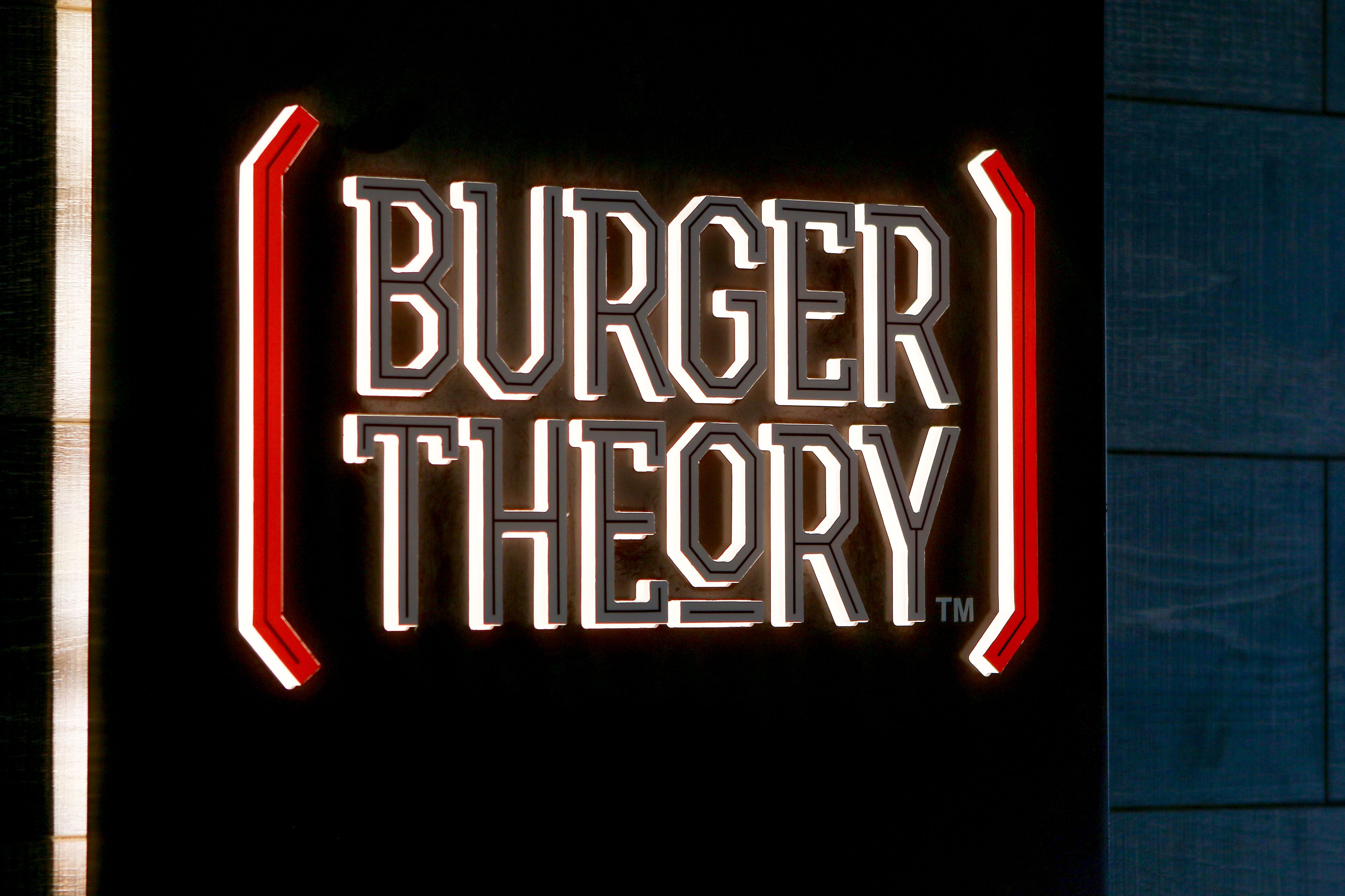 A neon sign with the text "BURGER THEORY" in a stylized font.