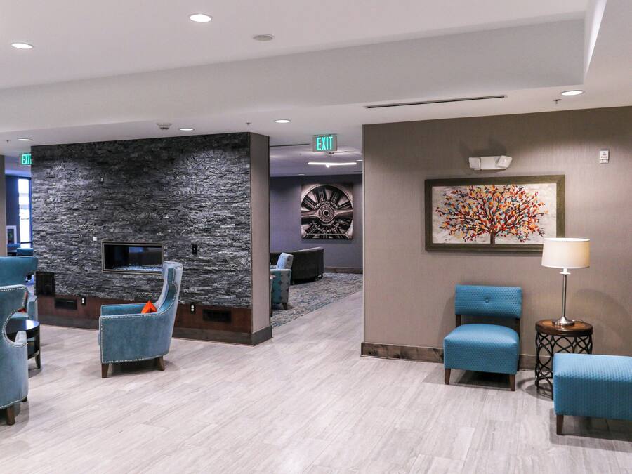 A lobby with stone walls, a fireplace, and blue upholstered chairs.