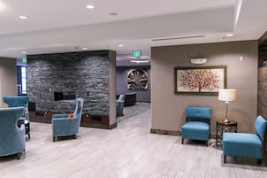A lobby with stone walls, a fireplace, and blue upholstered chairs.