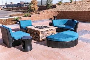 An outdoor seating area with a stone fire pit, cushioned chairs, and a small table. - Holiday Inn & Suites Denver Tech Center-Centennial by IHG (Centennial)