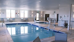 Une grande piscine intérieure équipée de plusieurs dispositifs d’élévation pour faciliter l’accès à l’eau, de chaises et d’une paroi en verre.