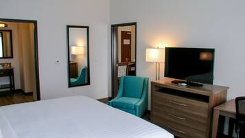Habitación de hotel con una cama grande, televisión, escritorio con cajones y una silla.