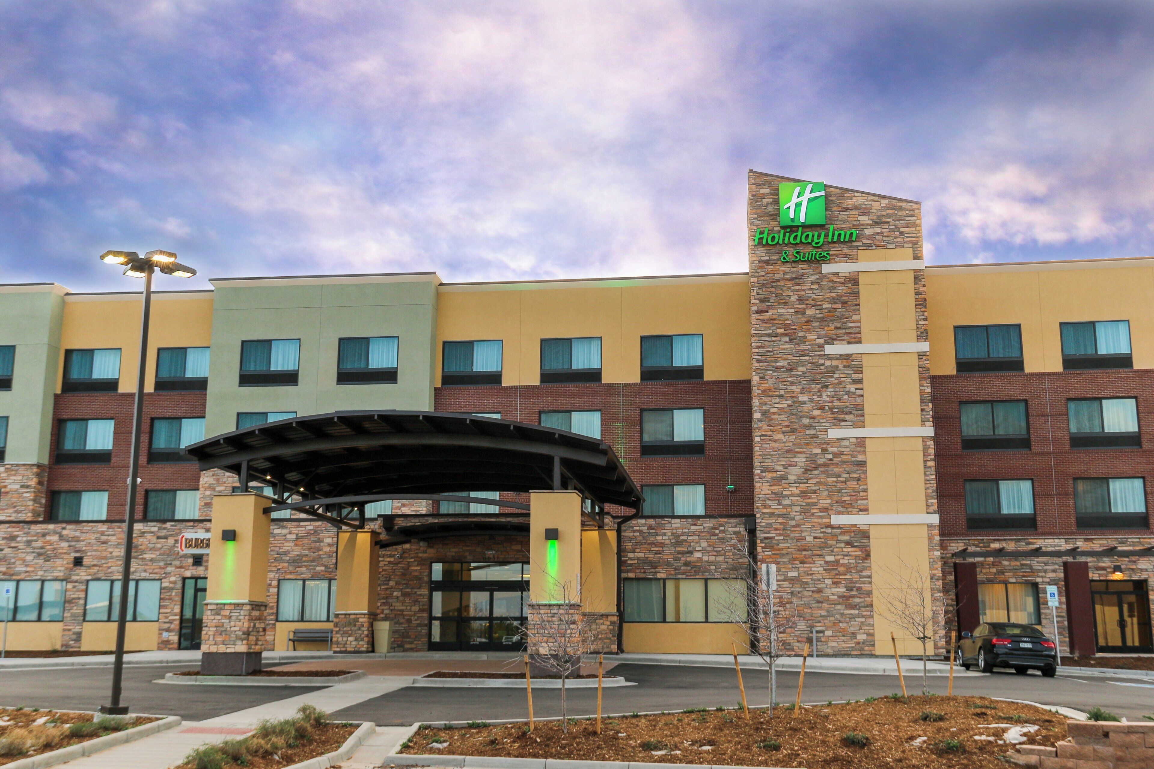 A Holiday Inn & Suites building with a brick facade, multiple windows, and a covered entrance area.