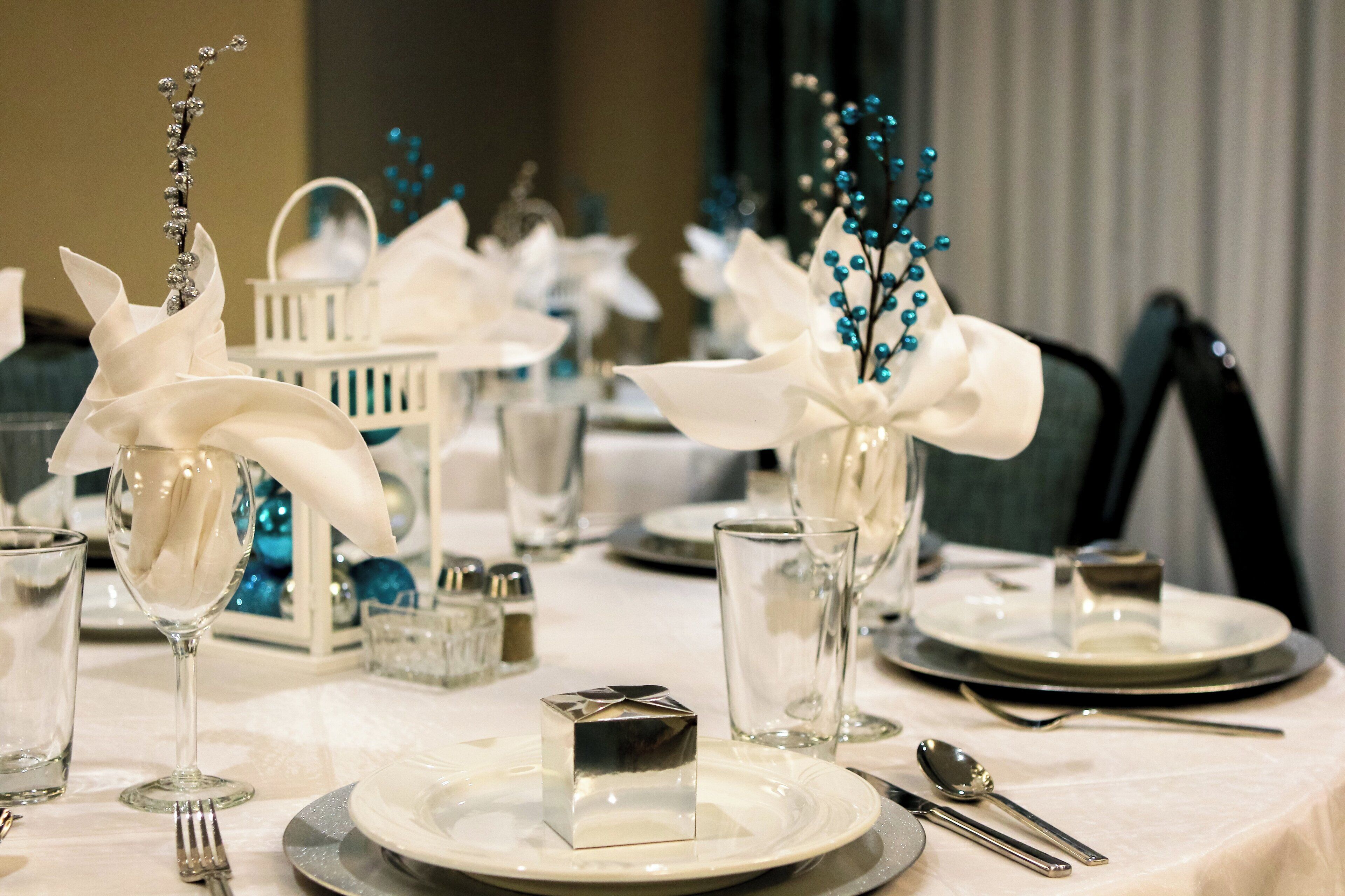 Une table dressée avec des assiettes, des verres, des couverts et des compositions florales décoratives.