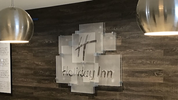 L'espace d'accueil d'un hôtel Holiday Inn, doté d'un design moderne, avec un mur en bois et une enseigne bien visible portant le logo de l'hôtel.
