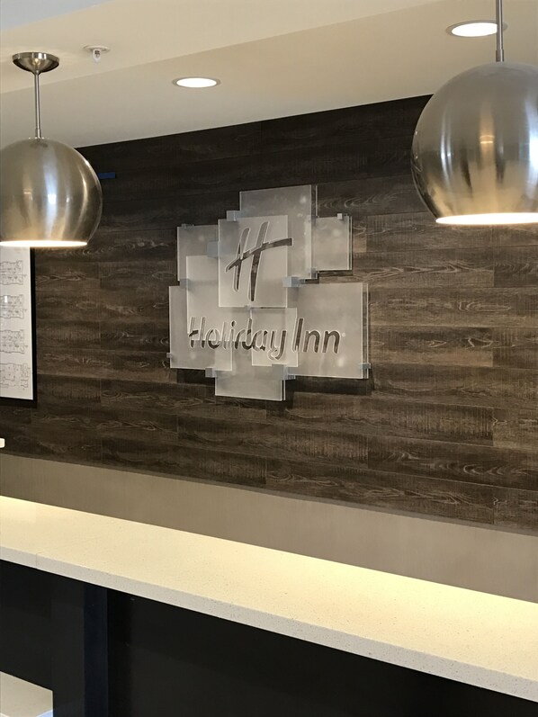 L'espace d'accueil d'un hôtel Holiday Inn, doté d'un design moderne, avec un mur en bois et une enseigne bien visible portant le logo de l'hôtel.