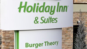 Une enseigne Holiday Inn & Suites avec un logo vert et le nom « Burger Theory » en dessous.