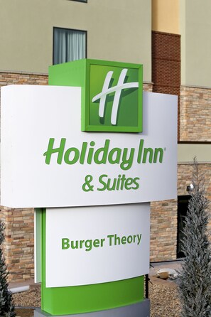 Une enseigne Holiday Inn & Suites avec un logo vert et le nom « Burger Theory » en dessous.
