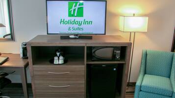 Habitación de hotel con cartel de Holiday Inn, un escritorio con lámpara, un microondas y una silla.