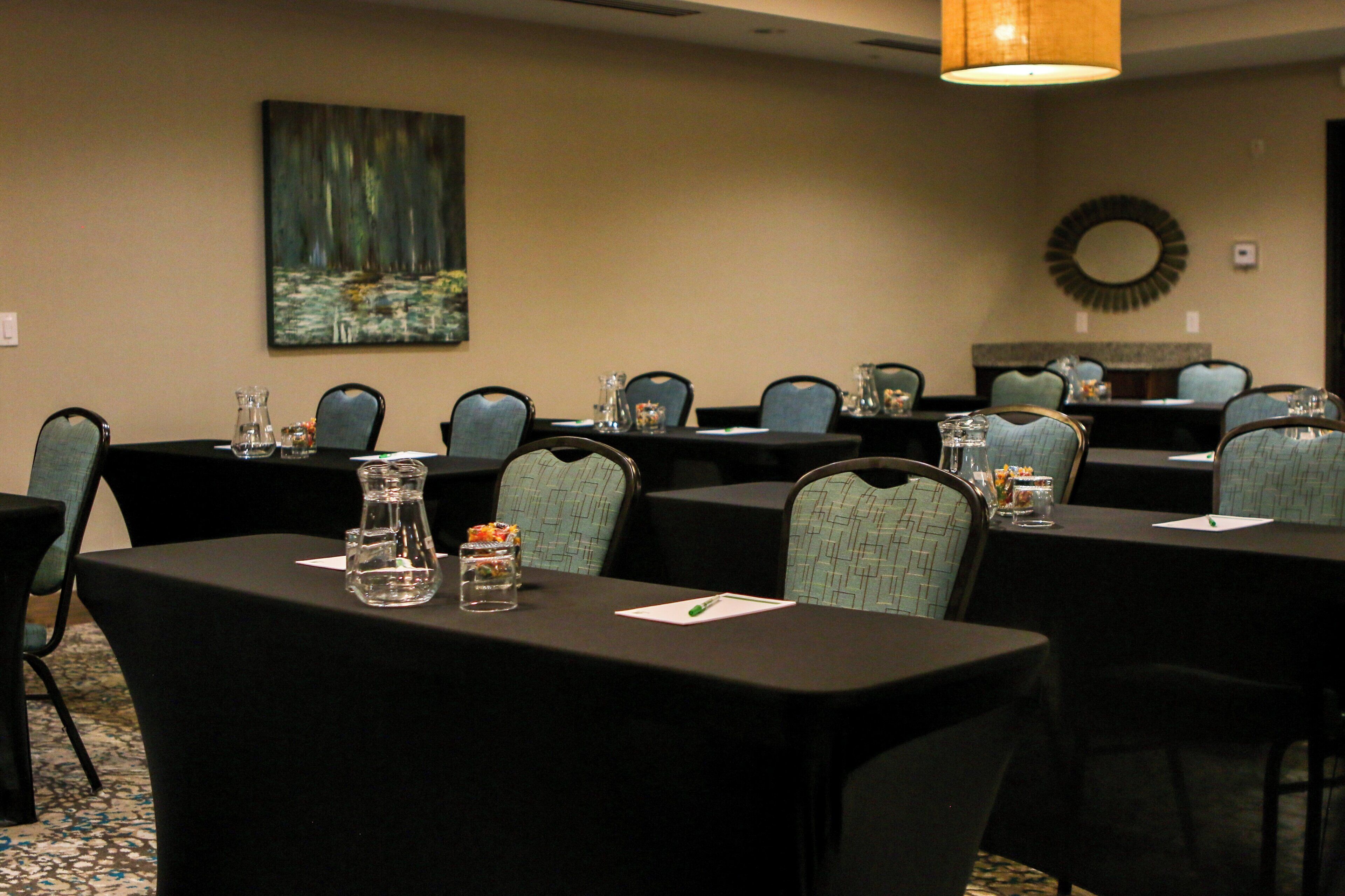 A conference room with tables, chairs, and a painting on the wall.