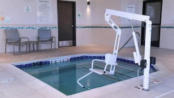 A pool area with a lift chair, a sign indicating pool rules, and a sign for the spa rules.