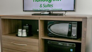 Une enseigne Holiday Inn & Suites au-dessus d’un meuble en bois contenant un four à micro-ondes et une machine à café.