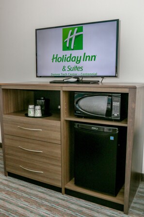 Une enseigne Holiday Inn & Suites au-dessus d’un meuble en bois contenant un four à micro-ondes et une machine à café.