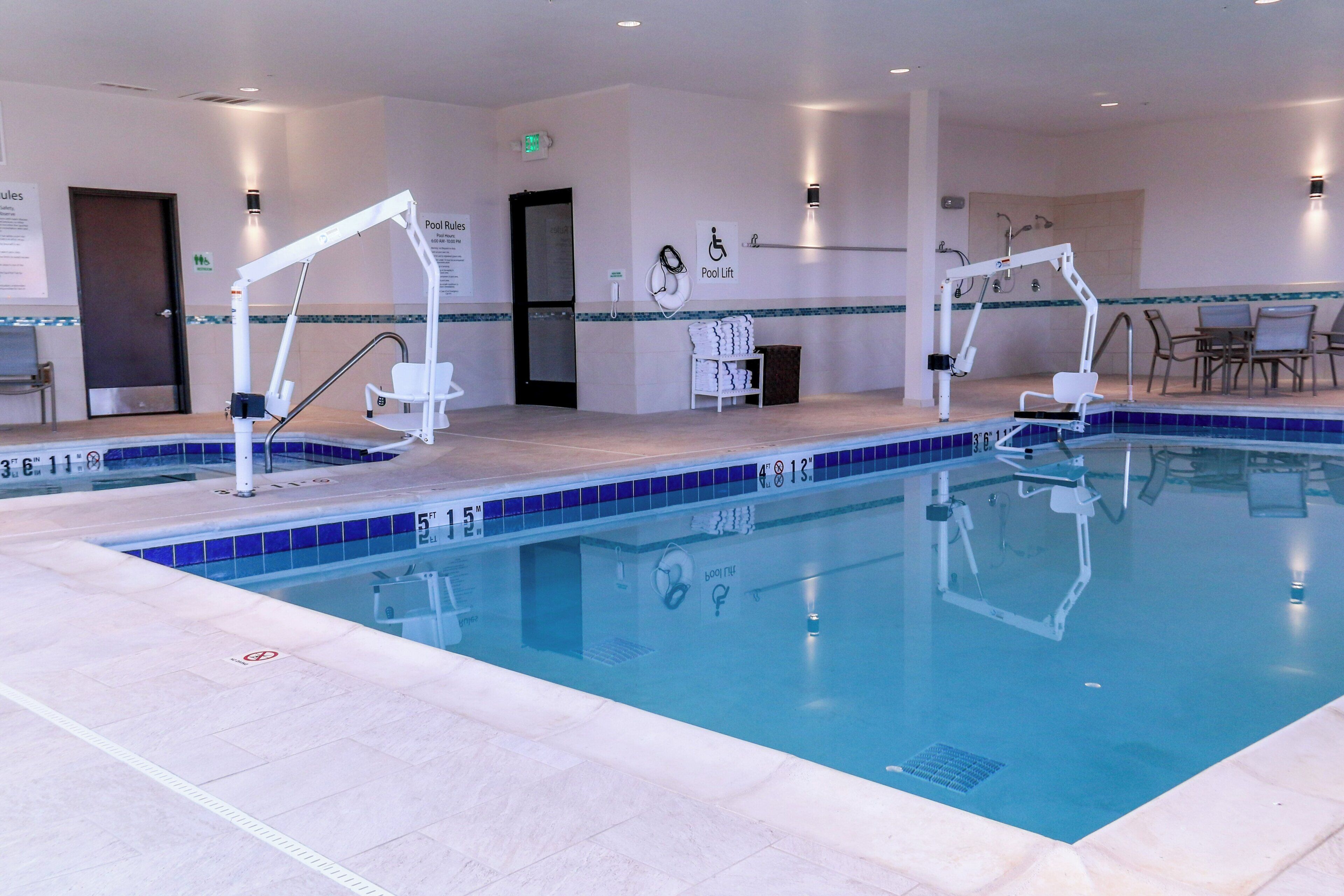 A swimming pool with two lifts, a changing room, and a poolside area with chairs.