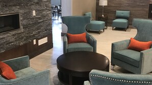 Un espace de détente moderne avec des fauteuils turquoise, une table basse centrale et un mur d’accent en pierre.