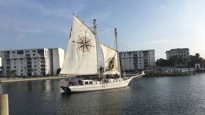 Un velero amarrado en un puerto deportivo con edificios modernos al fondo.