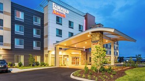 Een Fairfield Inn & Suites Marriott hotel met een modern design, met een opvallende ingang en een aangelegde groenstrook ervoor.