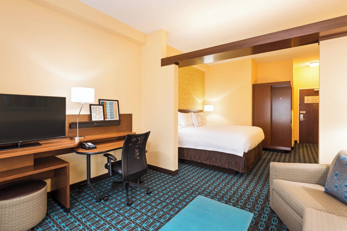 Una habitación de hotel con cama, escritorio con computadora, televisor y sofá.