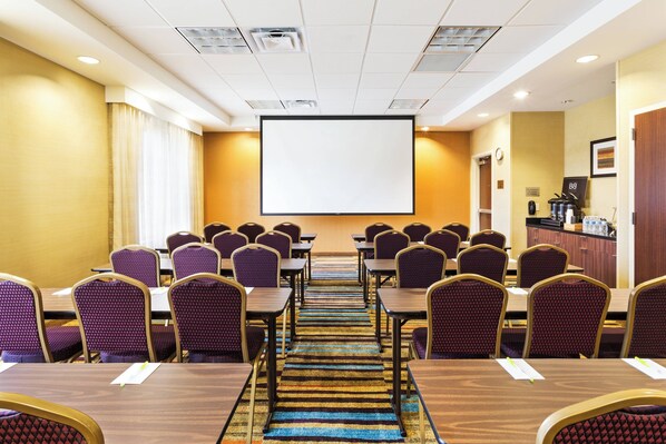 A conference room with rows of tables and chairs, a large projection screen, and a kitchenette area. - Fairfield Inn & Suites by Marriott Johnson City (Johnson City)