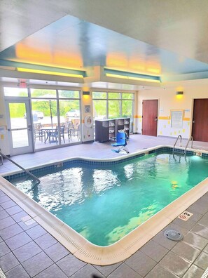 An indoor swimming pool with clear glass walls, a blue pool chair, and a tiled floor. - Fairfield Inn & Suites by Marriott Johnson City (Johnson City)