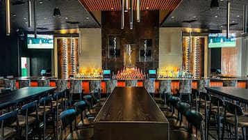 A bar area with a long counter, multiple seating arrangements, and a modern ceiling design.