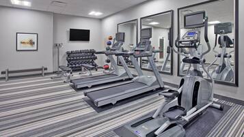 A gym with treadmills, elliptical machines, and a mirror wall.
