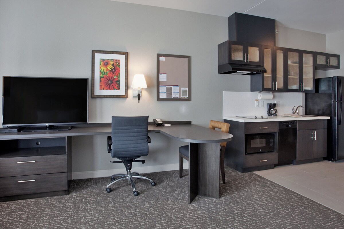 A modern kitchen with a built-in microwave, a refrigerator, and a coffee maker.