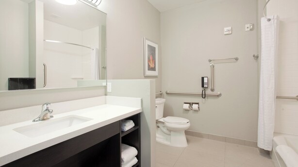 Un baño moderno con lavamanos, inodoro y zona de ducha blancos.