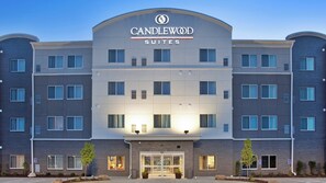 Ein mehrgeschossiges Hotel mit einem auffälligen 'CANDLEWOOD SUITES' Schild, einer Ziegel-Fassade und einem zentralen Eingang mit Glastüren.