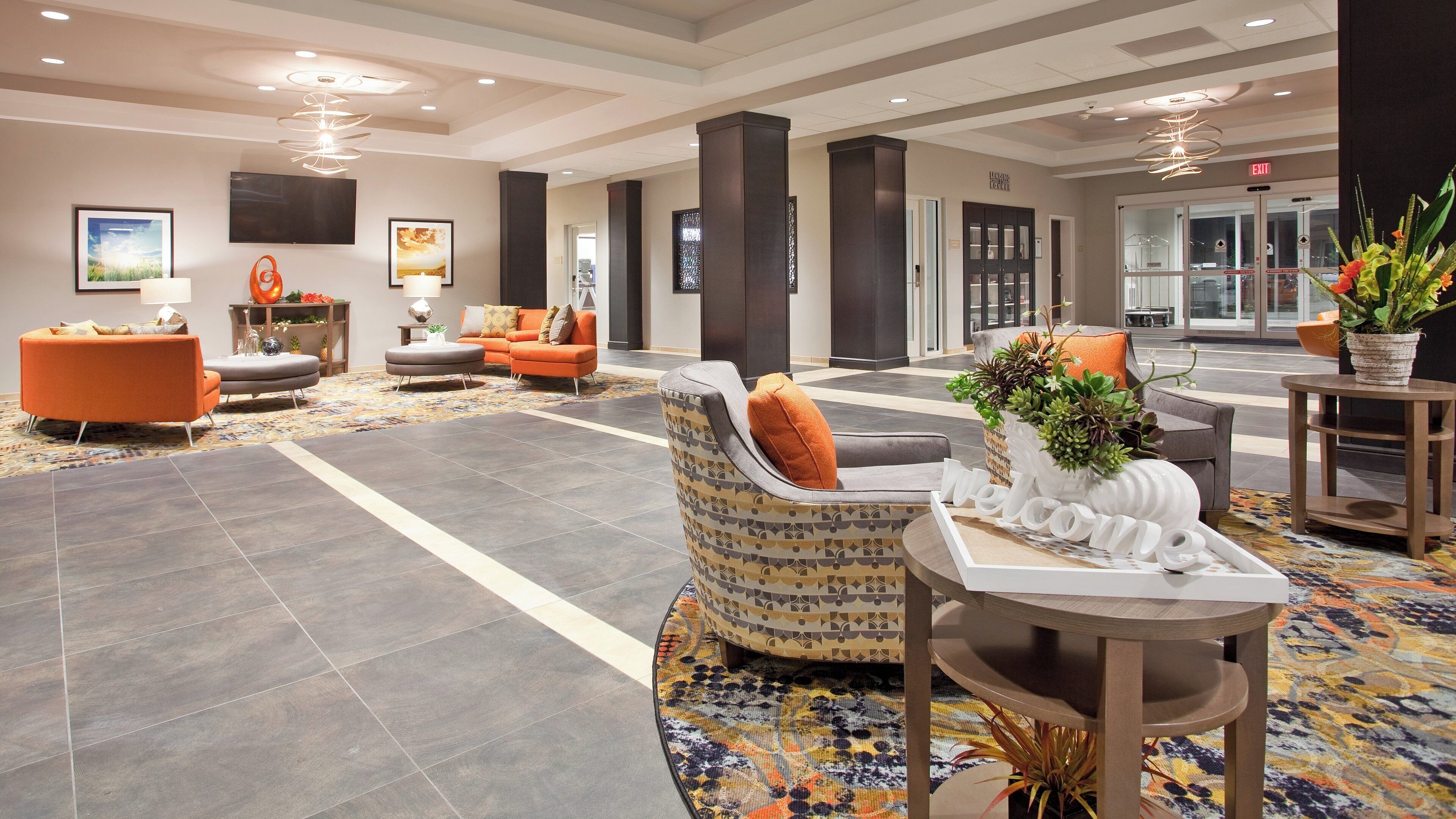 A hotel lobby with a reception desk, seating area, and a 'Welcome' sign.