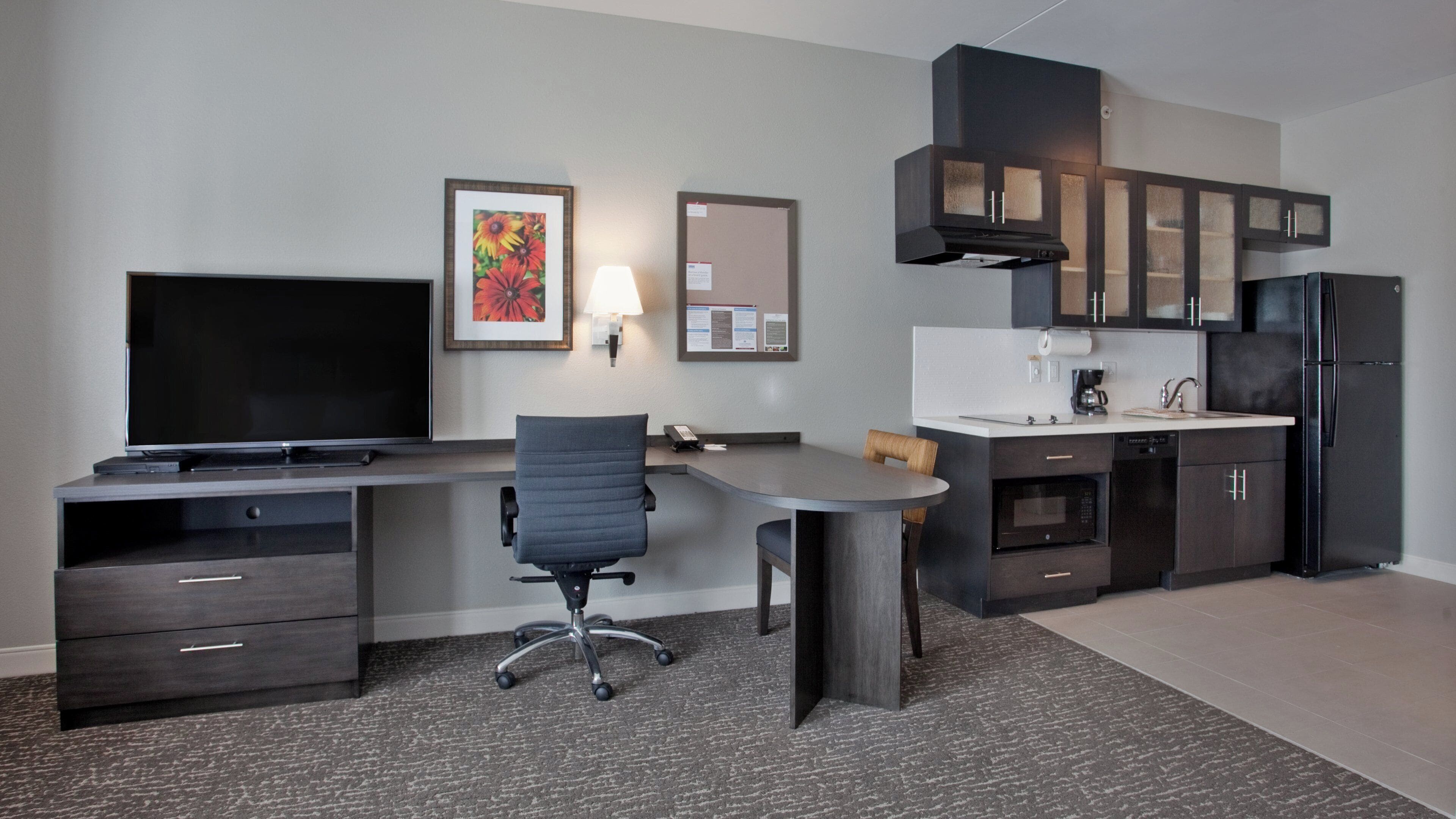 A modern kitchen with a built-in microwave, refrigerator, and a coffee maker.