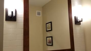 A hotel bathroom with a large mirror, a sink, a towel rack, and a framed picture on the wall.