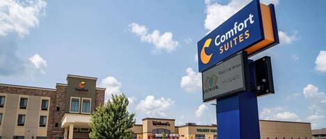 Un hotel con un letrero de Comfort Suites, un restaurante B&B Grill y un edificio Wilbert Suites.